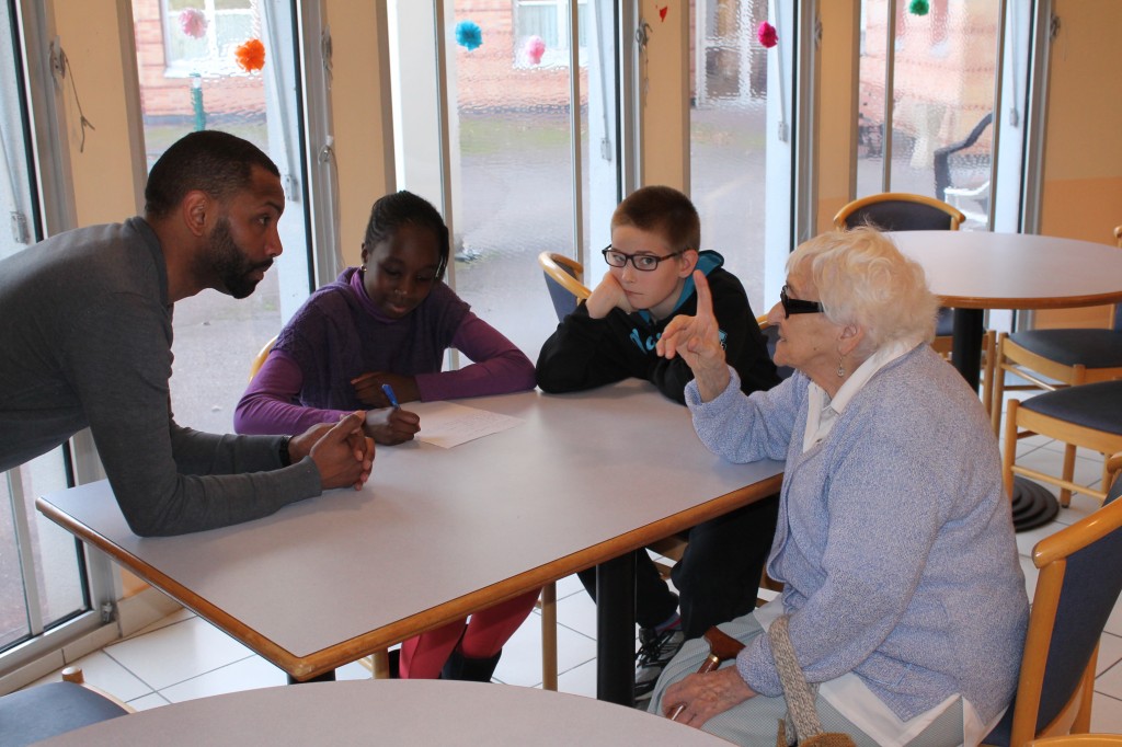 L’Espace Laïque Vernonnais porte le projet « Lieu de mémoire », en partenariat avec les centres sociaux de la ville (Espace Simone-Veil et Pénitents). Des jeunes âgés de 12 à 14 ans ont choisi des lieux de mémoire (monuments, lieux historiques…) du territoire, afin de réaliser des affiches à leur effigie. Ils sont partis à la rencontre des anciens (ci-dessus, à l'EHPAD Auguste-Ridou) qui ont pris plaisir à relater leurs souvenirs autour des sites sélectionnés. Ce projet a donc permis des rencontres intergénérationnelles, avec l'organisation d'un goûter avec les personnes âgées, ainsi que d'une journée pique-nique et visite de la ville. Les jeunes avaient à cœur d’aider les personnes âgées et de partager un moment citoyen avec eux. Un après-midi diffusion de photos et de films d’avant-guerre (proposé par Alexandre Révérend) a permis aux enfants de découvrir leur ville à une période qu’ils n’ont pas connue. Forts du travail de recherche accompli, ils organisent une exposition, qui se déplacera dans différents lieux de la ville durant plusieurs mois. Elle sera visible : - à l'espace Simone-Veil jusqu'au 1er juillet, - dans le hall de la mairie de Vernon du 5 juillet au 1er septembre, - au centre social des Pénitents du 1er septembre au 9 octobre, - à l'EHPAD Auguste-Ridou du 9 au 15 octobre. Elle viendra ensuite compléter « Espace dans ma Ville » à Simone-Veil du 30 octobre au 3 novembre. À la suite de ce circuit, l’exposition devrait circuler au sein des collèges. 