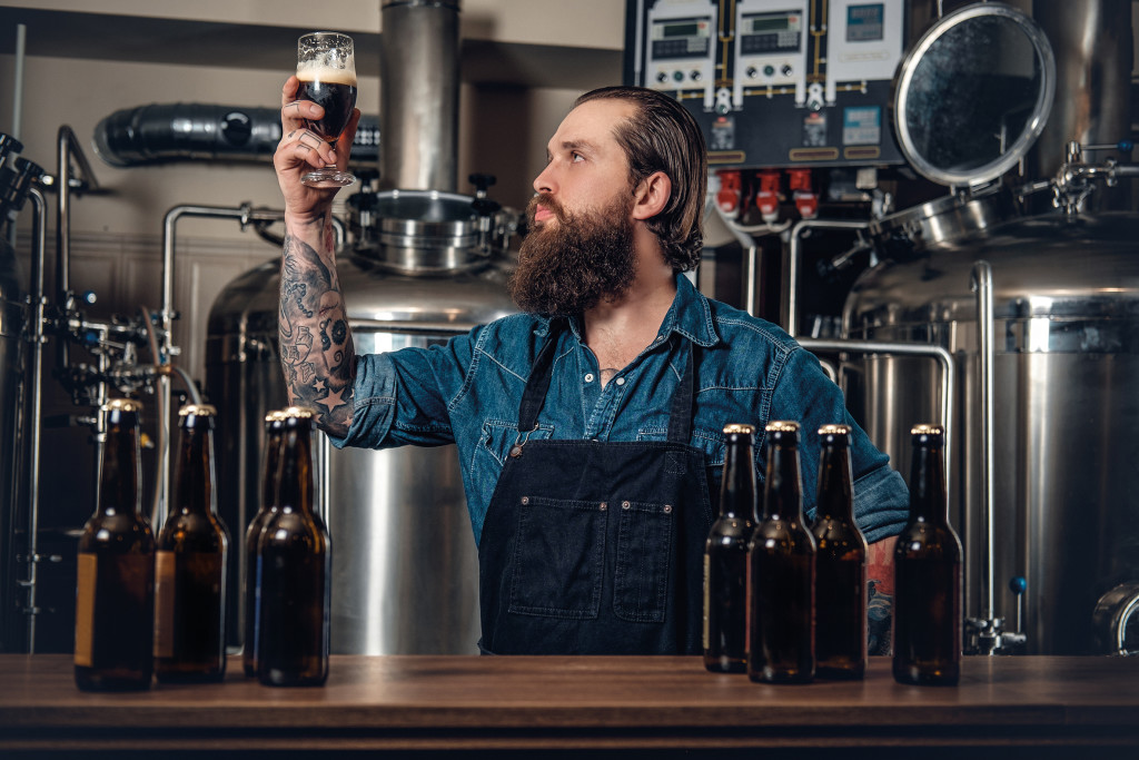 Portrait,Of,Tattooed,,Bearded,Hipster,Male,Manufacturer,Tasting,Beer,In