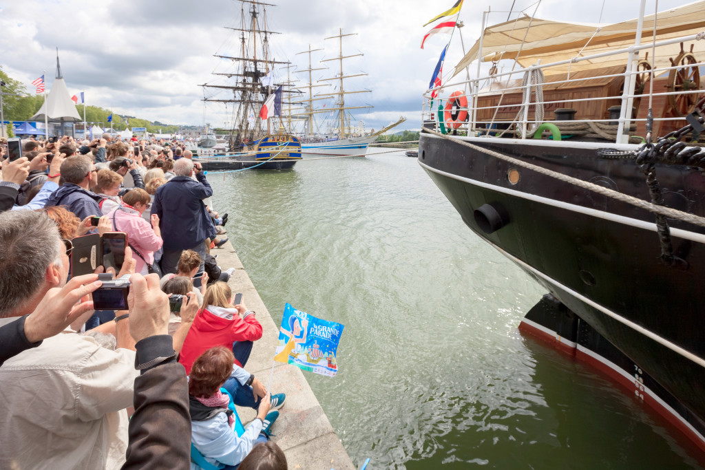 ROUEN, NORMANDY, FRANCE - June 16, 2019: Armada gathering of tall ships on the Seine river, visitors wave at sailors as they manoeuvre to leave the docks