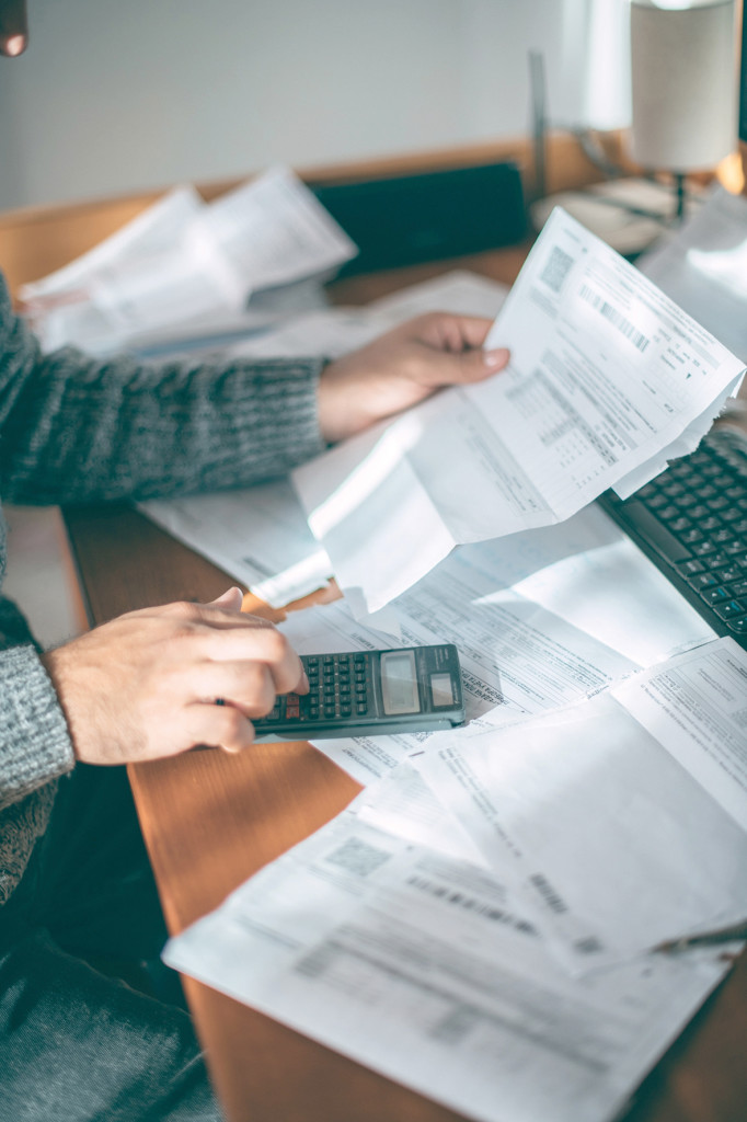 Close-up of male hands with a utility bill, a lot of checks and a calculator on the table. The man considers the costs of gas, electricity, heating. The concept of increasing tariffs for services