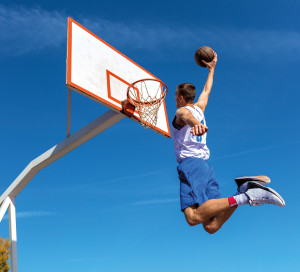 Young Basketball street player making slam dunk