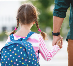 first day at school. father leads a little child school girl in first grade