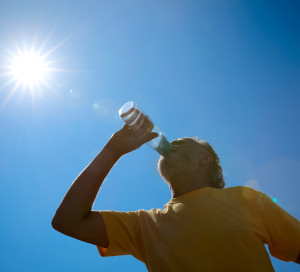 Senior man drinking water to prevent heat stroke outdoors, low angle view