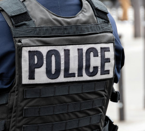 Close-up 'POLICE' marking written on the back of a bulletproof vest worn by a French police officer on a street in Paris, France. Concepts of law enforcement, crime, delinquency and criminal affairs