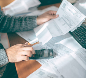 Close-up of male hands with a utility bill, a lot of checks and a calculator on the table. The man considers the costs of gas, electricity, heating. The concept of increasing tariffs for services
