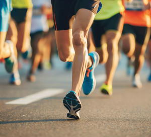 Close-Up of Marathon Runners' Legs on City Road During Athletic Competition.