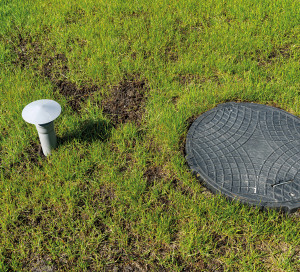 Hatch and vent from a household septic tank with no outflow placed in the garden.