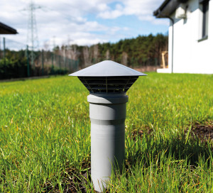A gray vent pipe from a household septic tank without a drain located in the garden.